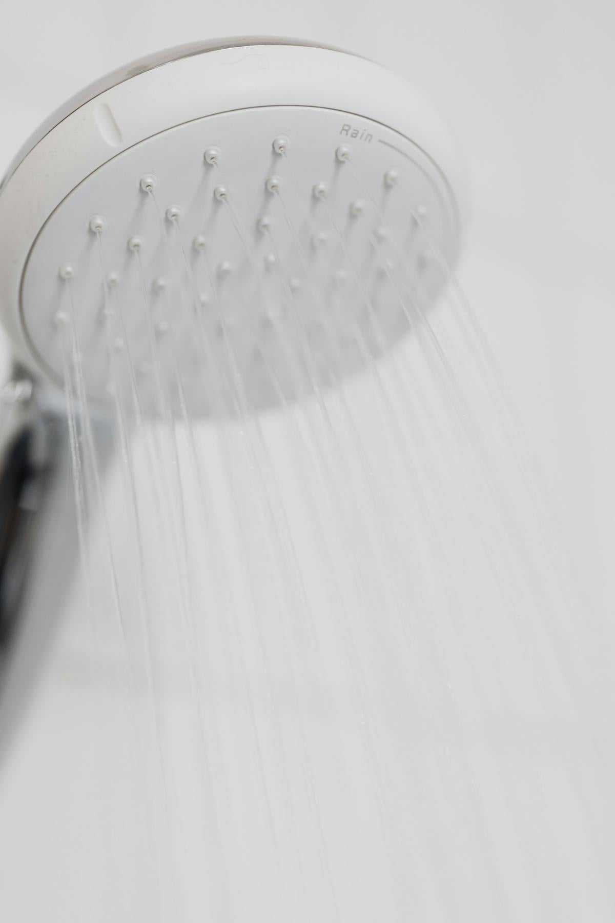 Limescale buildup on a South Florida bathroom faucet next to a water softener tank